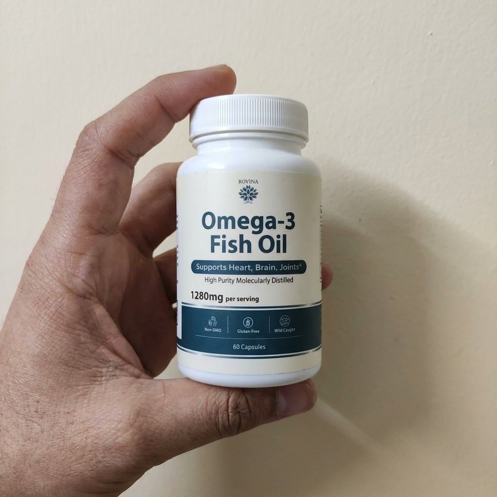 Hand holding Rovina Omega-3 Fish Oil against a wall